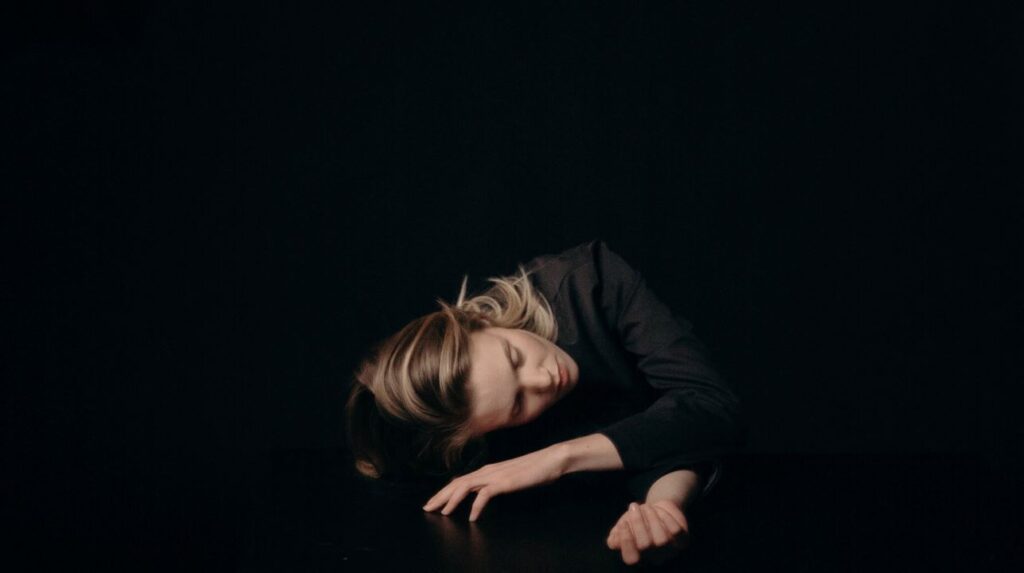 Woman in Black Long Sleeved Shirt Sleeping on Table