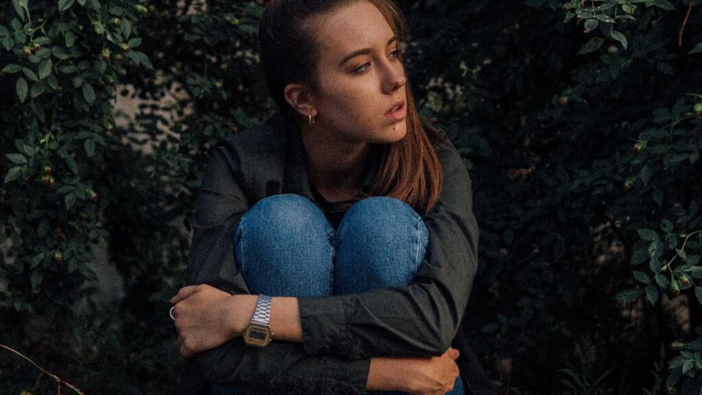 Girl crouching in shrubbery