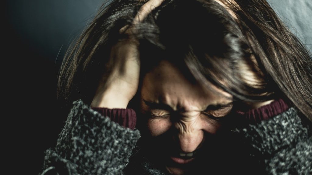 Distressed woman clutching her head in her hands.
